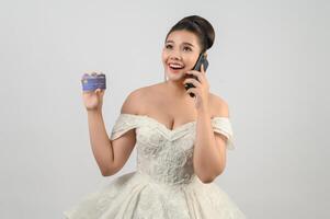 jong Aziatisch mooi bruid posten met credit kaart en smartphone in hand- foto