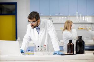 onderzoeker in witte laboratoriumjas werken met laptop zittend in het lab foto