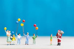miniatuur kerstman en kinderen met ballonnen, prettige kerstdagen en gelukkig nieuwjaar concept