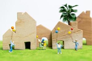 miniatuurfamilie die in een veld loopt met ballonnen, gelukkige familierelaties en zorgeloos vrijetijdsconcept foto