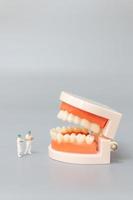 miniatuur tandarts die menselijke tanden met tandvlees en glazuur, gezondheids en medisch concept herstelt foto