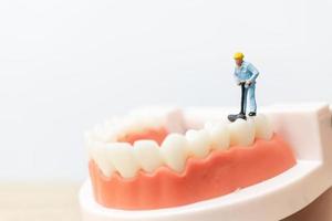 miniatuurarbeiders die een tand, gezondheidszorg en medisch concept herstellen foto