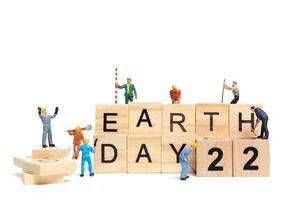 miniatuurarbeiders die samenwerken om het woord aarde dag 22 te bouwen op houten blokken, het concept van de dag van de aarde foto