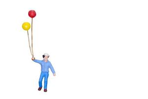 miniatuur persoon met ballonnen geïsoleerd op een witte achtergrond foto