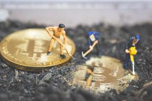 miniatuurarbeiders die de grond graven om glanzende bitcoin cryptocurrency, succesvol werkconcept te ontdekken foto