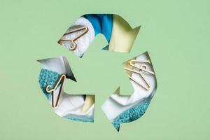 kleurrijk kleren en mini honger onder papier besnoeiing recycling symbool. tweede hand, kleding bijdrage en recycling concept foto