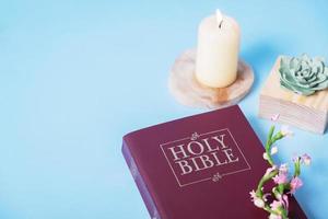 christen heilig Bijbel met kaars Aan blauw achtergrond, vlak leggen, top visie foto