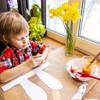 jongen tekening de oren van een handgemaakt Pasen konijn gemaakt van karton. voorbereiding voor de viering van de Pasen vakantie. foto