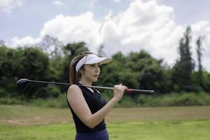 portret van golfspeler Aziatisch vrouw Holding golf hout Bij de land club, gelukkig vrouw begrip, gezet golf Aan pin foto