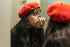 jong elegant meisje aan het doen haar bedenken met eyeliner foto