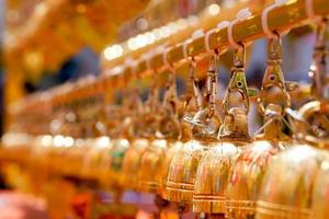 detailopname en perspectief visie groep van klein gouden klokken hangen in Thais tempel Aan wazig achtergrond. foto