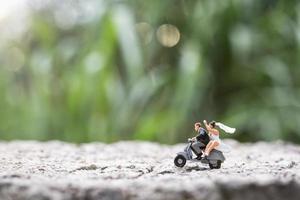 miniatuurpaar die een motorfiets berijden op een vage aardachtergrond foto