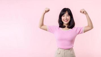 portret jong Aziatisch vrouw trots en zelfverzekerd tonen sterk spier sterkte armen gebogen poseren, voelt over haar succes prestatie. Dames machtiging, gelijkwaardigheid, gezond sterkte en moed concept foto