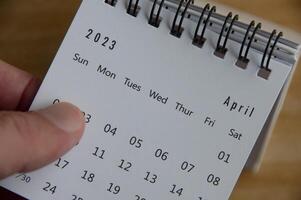 top visie van hand- flippen april 2023 kalender. kalender concept foto