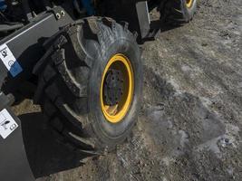 close-up van een vuil laderwiel met een groot loopvlak en een gele rand foto