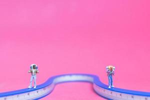 miniatuurpaar reizigers op een brug met een roze achtergrond foto
