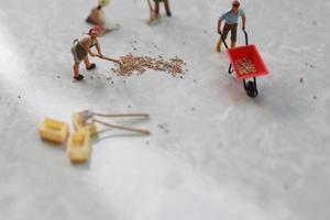 miniatuur figuren van arbeiders werken samen naar Actie korrel. foto