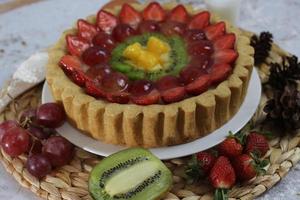 groot fruit taart met toppings van aardbeien, druiven, kiwi en ananas. hartig, zoet en vers. voedsel concept foto. foto