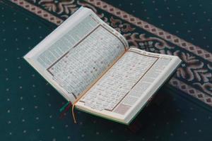 een dichtbij omhoog van de heilig boek al-koran Aan een groen gebed tapijt. Islamitisch foto concept.