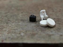 een dichtbij omhoog van een miniatuur figuur van een onderzoeker onderzoeken een medicijn. Gezondheid foto concept.