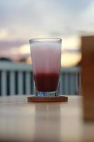 een glas van rood fluweel latte geserveerd verkoudheid Aan de tafel. foto