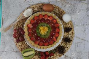 groot fruit taart met toppings van aardbeien, druiven, kiwi en ananas. hartig, zoet en vers. voedsel concept foto. foto