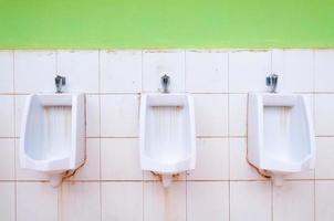 lijn van wit porselein urinoirs in openbaar Toiletten, vuil Toiletten buitenshuis foto