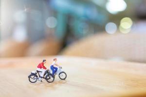 miniatuurmensen fietsen op een houten brug, zorgconcept foto