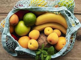 mesh boodschappentas met biologisch fruit op houten achtergrond foto