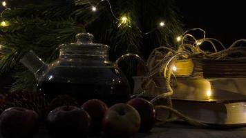 glas theepot, oud boeken, pijnboom bomen en appels. slinger lichten. nacht afbeelding. Kerstmis humeur. foto