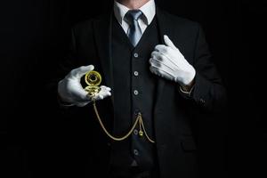 portret van butler in donker pak en wit handschoenen Holding goud zak- horloge. wijnoogst stijl en professioneel beleefdheid. foto