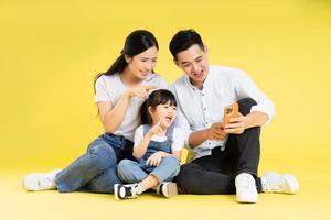 beeld van Aziatisch familie zittend samen gelukkig en geïsoleerd Aan geel achtergrond foto