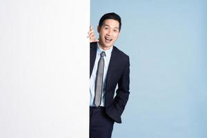 portret van aziatische zakenman die pak op blauwe achtergrond draagt foto