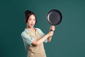 Aziatisch vrouw vervelend schort en Holding een pan foto