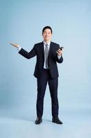 portret van aziatische zakenman die pak op blauwe achtergrond draagt foto