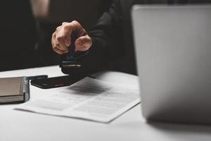 zakenman hand- stempelen goedgekeurd Aan certificaat document contract in kantoor. advocaat stempelen toestaan Aan papierwerk Bij houten bureau. foto