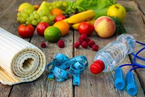 fruit, groenten, water, meting plakband en sport- goederen Aan houten achtergrond. foto