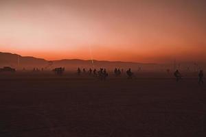 mensen wandelen naar zonsondergang Bij een festival in de woestijn Bij de brandend Mens festival. foto