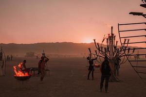 mensen wandelen naar zonsondergang Bij een festival in de woestijn Bij de brandend Mens festival. foto