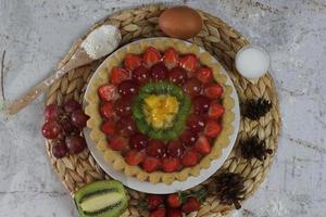 groot fruit taart met toppings van aardbeien, druiven, kiwi en ananas. hartig, zoet en vers. voedsel concept foto. foto