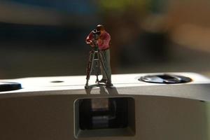 miniatuur figuur van een videograaf opname Aan een analoog camera. foto