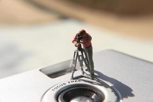 miniatuur figuur van een videograaf opname Aan een analoog camera. foto