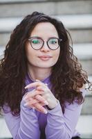 mooi jong vrouw met brunette gekruld haar, portret in oog bril genieten van de zon in de stad. foto