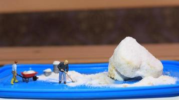 een miniatuur figuur van een arbeider opruimen een pinda taart besprenkeld met gepoederd wit suiker. concept van arbeiders in de voedsel industrie. foto