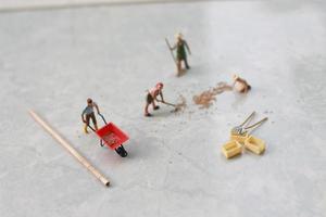 miniatuur figuren van arbeiders werken samen naar Actie korrel. foto