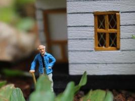 een dichtbij omhoog van een miniatuur figuur van een oud Mens aan het wachten in voorkant van de huis. foto