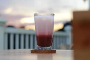 een glas van rood fluweel latte geserveerd verkoudheid Aan de tafel. foto