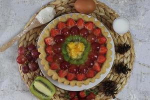 groot fruit taart met toppings van aardbeien, druiven, kiwi en ananas. hartig, zoet en vers. voedsel concept foto. foto