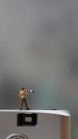 een miniatuur figuur nemen afbeelding met een camera tegen een echt camera in de achtergrond. foto