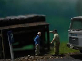 een dichtbij omhoog van een miniatuur figuur van een oud Mens pratend naar andere mensen in een oud gebouw door de kant van de weg. foto
